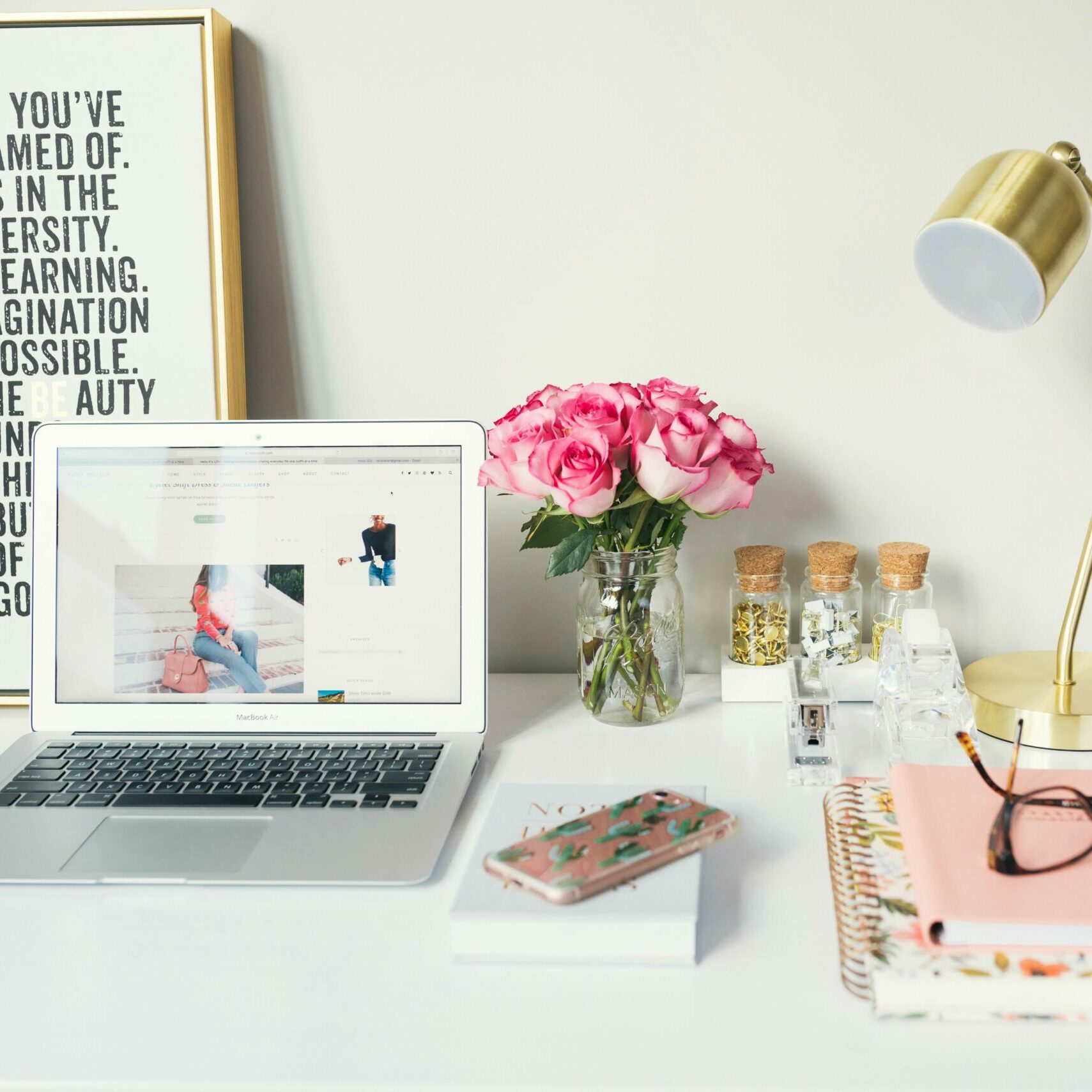 office desk with open laptop and pink diary